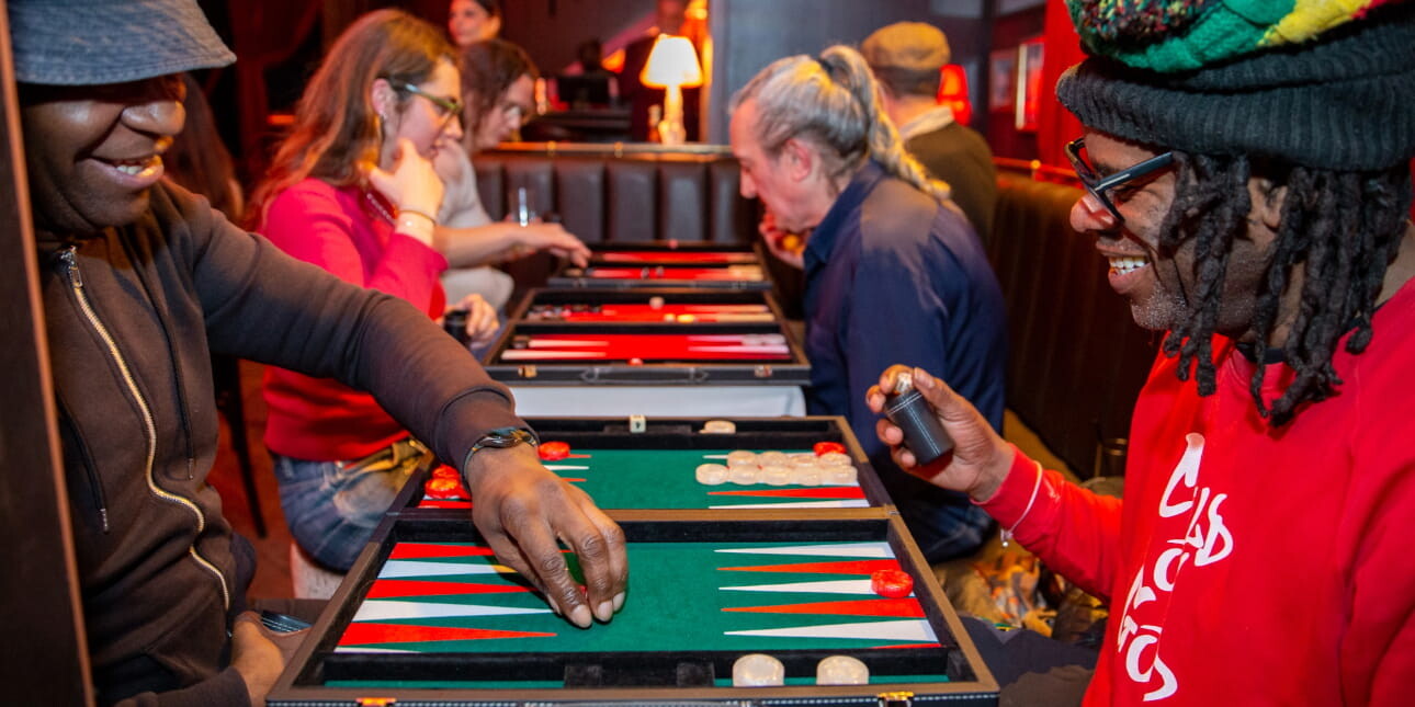 Two black men smiling while they play backgammon